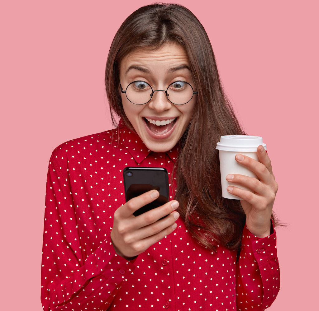 Chica emocionada viendo su teléfono.